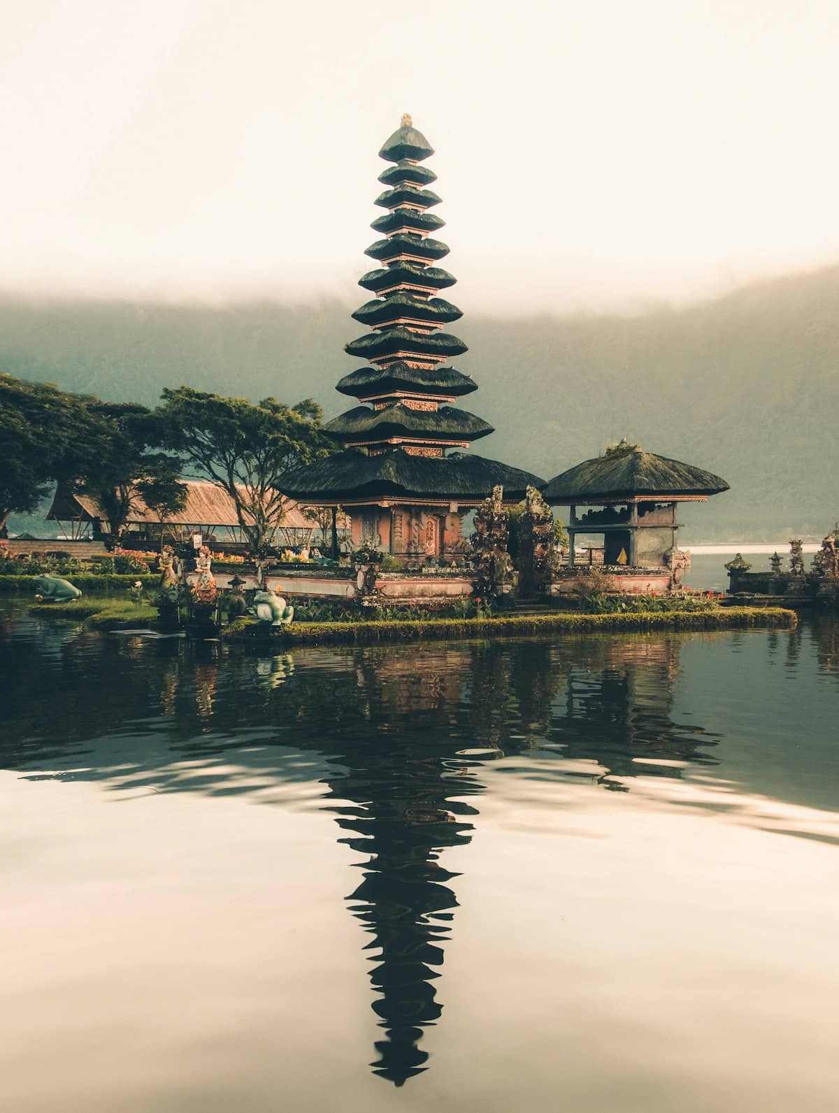 A lakeside temple in Bali surrounded by mist and trees