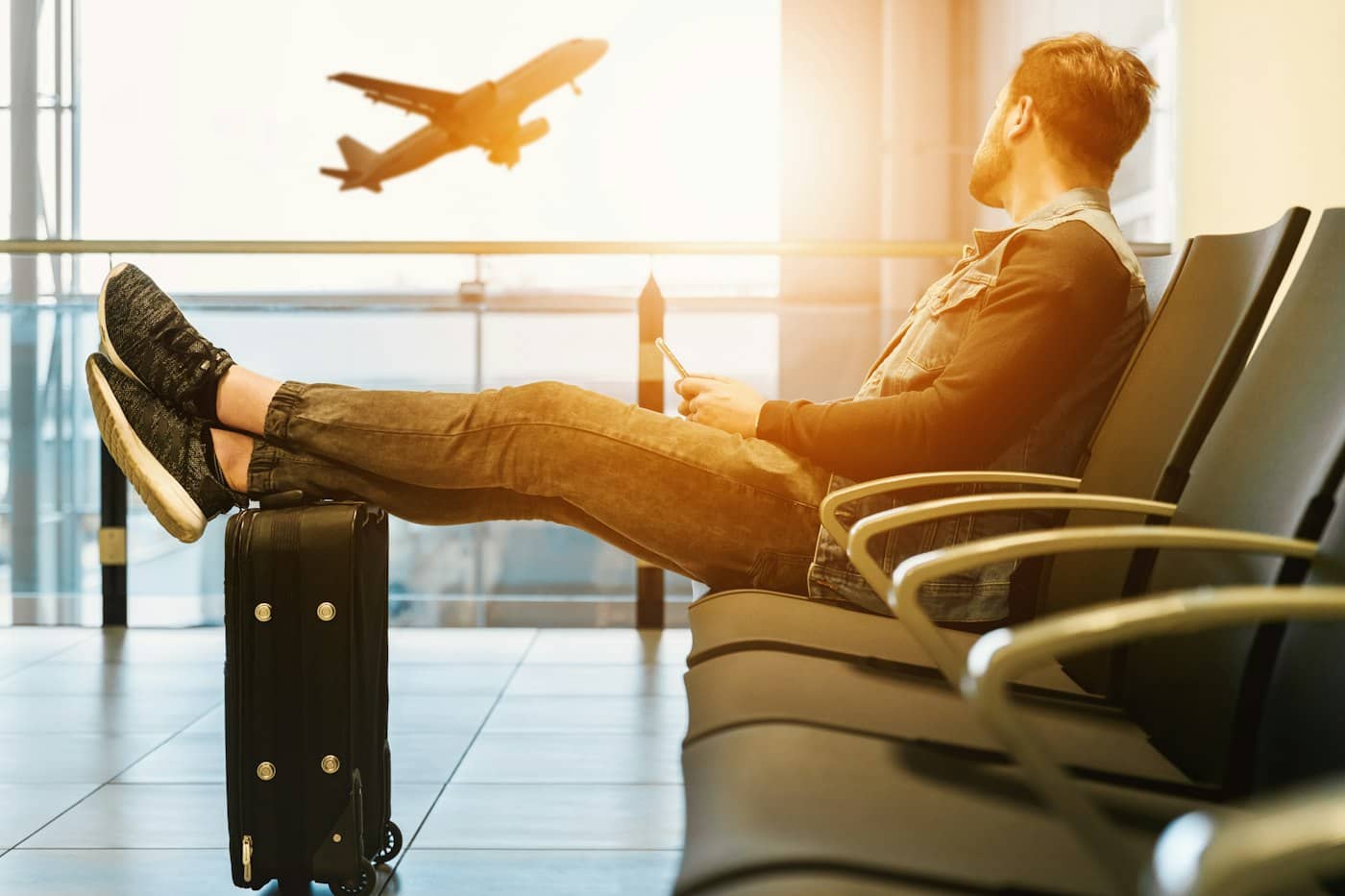 Traveller relaxing in an airport lounge while a plane takes off outside