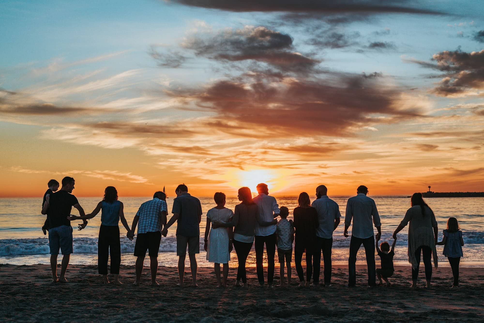 A family walking hand in hand along a beach at sunset