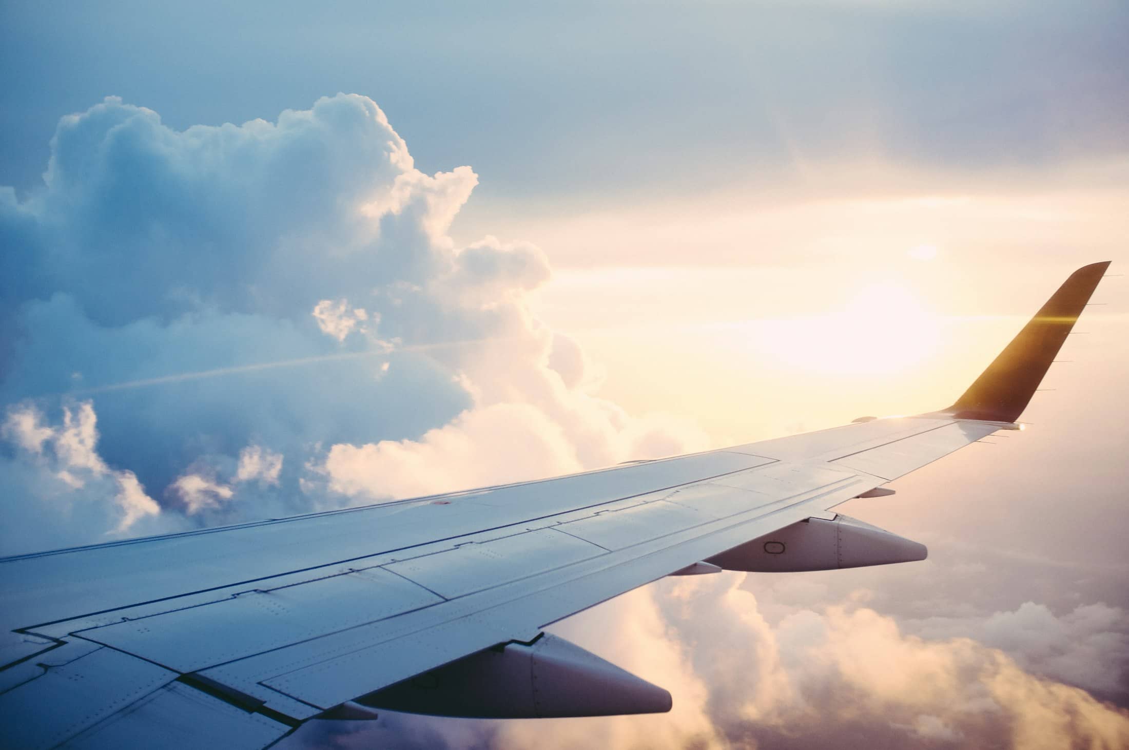 Aircraft wing above a layer of clouds in warm evening light