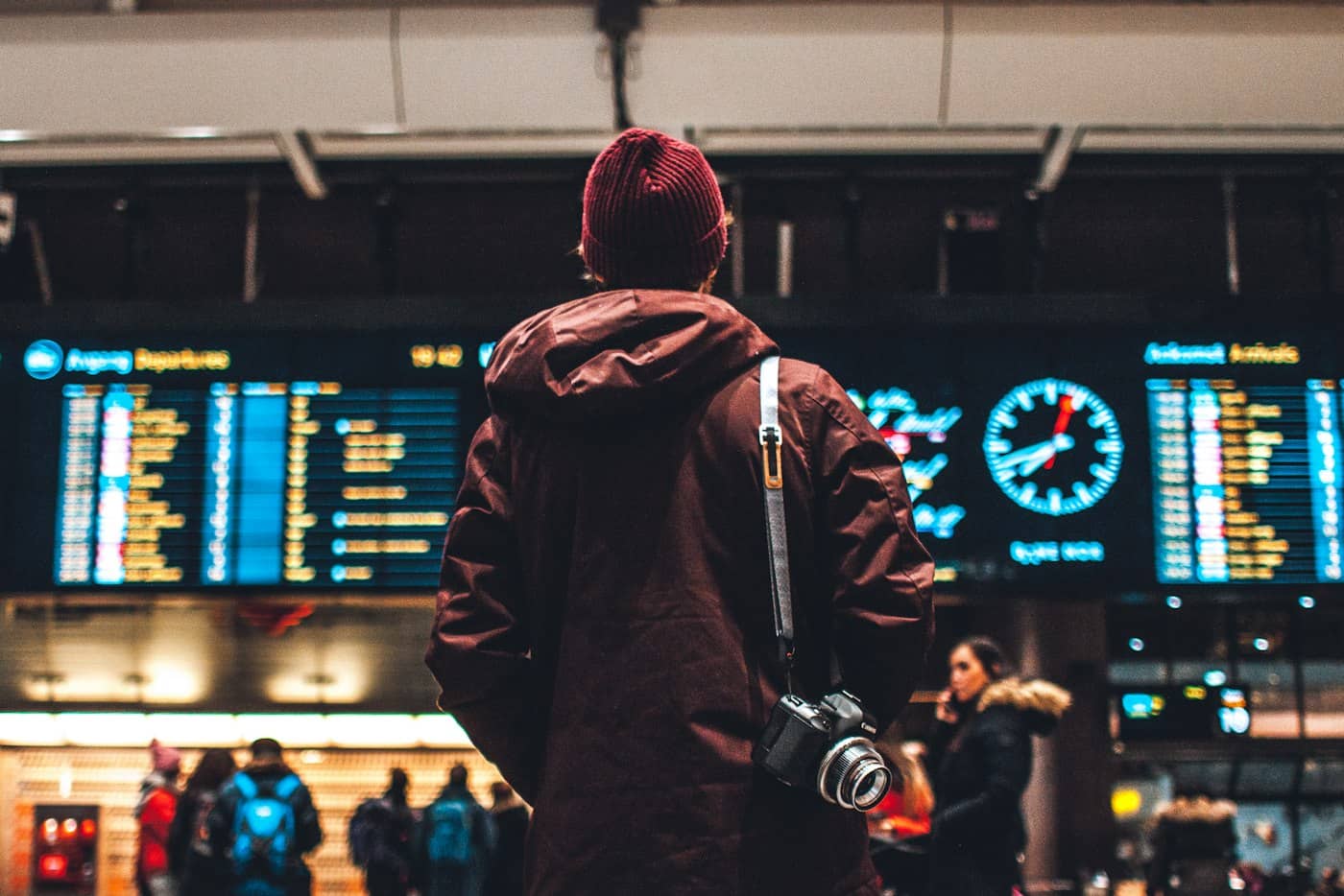 Traveller with a backpack reading the departures board in an airport terminal